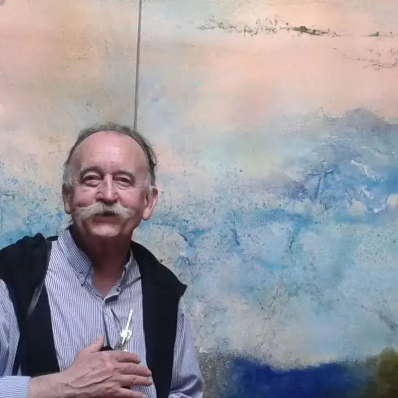 Portrait de Yannick Trévidy, souriant, devant une peinture aux tons bleus